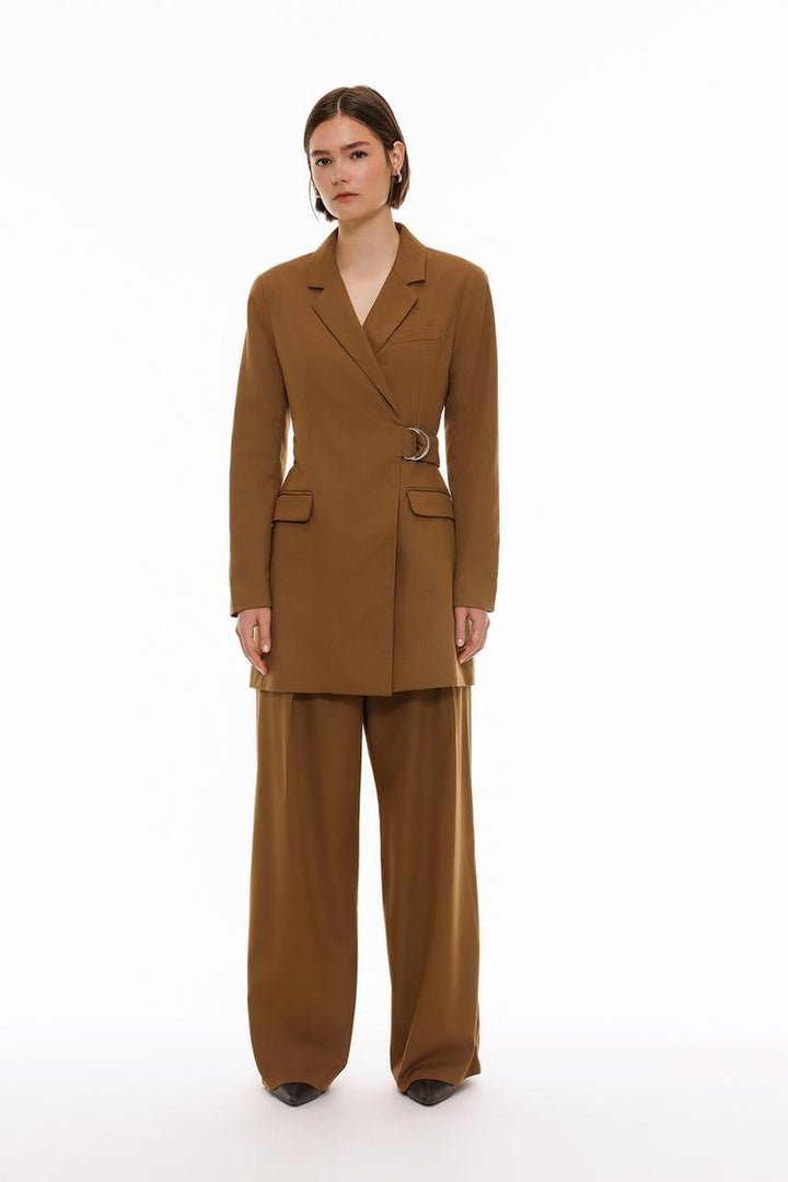 Image of brown pleated wide-leg trousers, emphasizing the pleated details and the loose, flowing fit that defines the design.