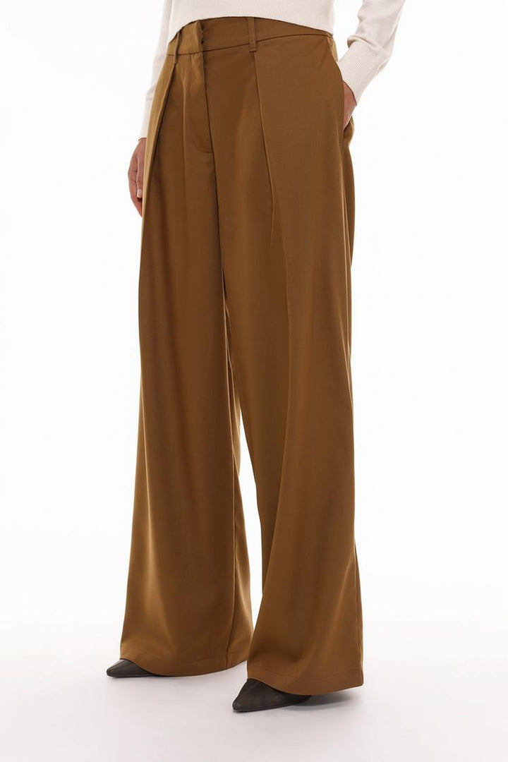 Full-body shot of someone wearing the brown pleated wide-leg trousers, showcasing how they look when styled as part of an outfit.