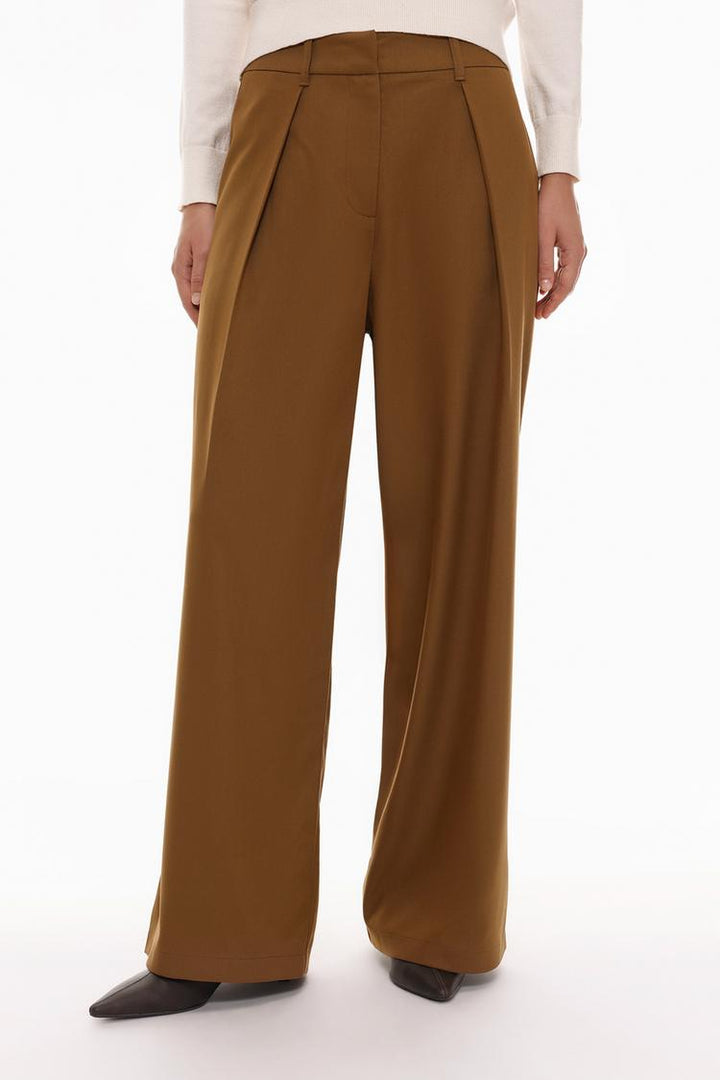 Front view of the brown pleated wide-leg trousers, highlighting the pleats and waistband, as well as the elegant flow of the fabric.