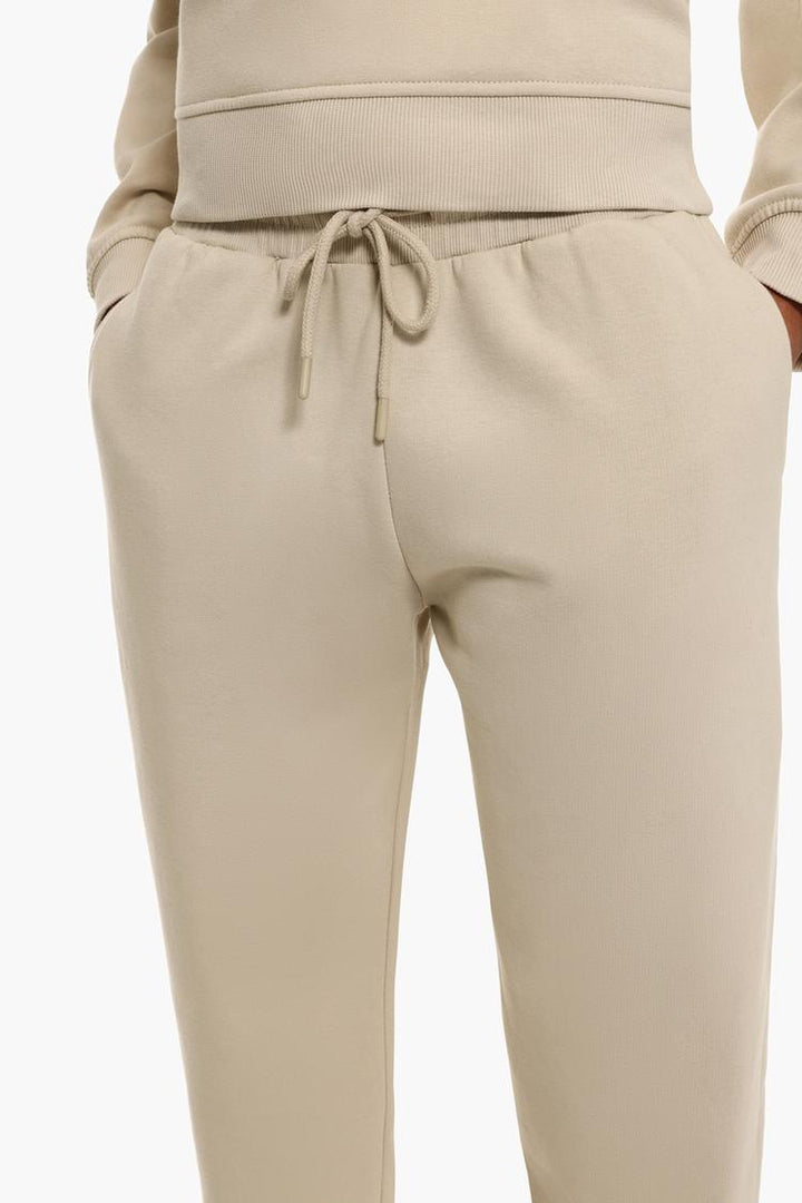 Zoomed-in shot of beige plush joggers focusing on the texture and fabric details.