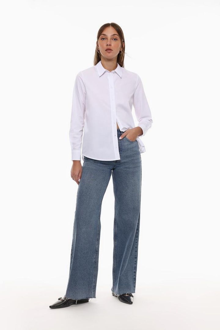 A full-body image of a poplin shirt would showcase the entire shirt, displaying its design from collar to hem. The shirt would typically be shown in a standing or model-worn position, illustrating how the fabric fits and moves. The image would highlight key details such as the button-down front, cuffs, collar, and any other stylistic features like pleats, darts, or pockets. It would offer customers a clear view of the shirt’s overall silhouette, making it easier for them to envision how it fits and how it m