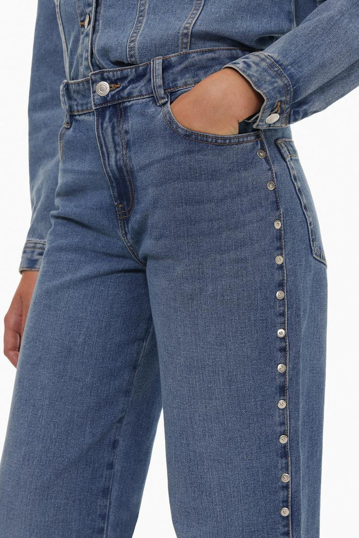 Side profile of the jeans, displaying the elegant tapering, side seam details, and the way the studs enhance the overall design.

