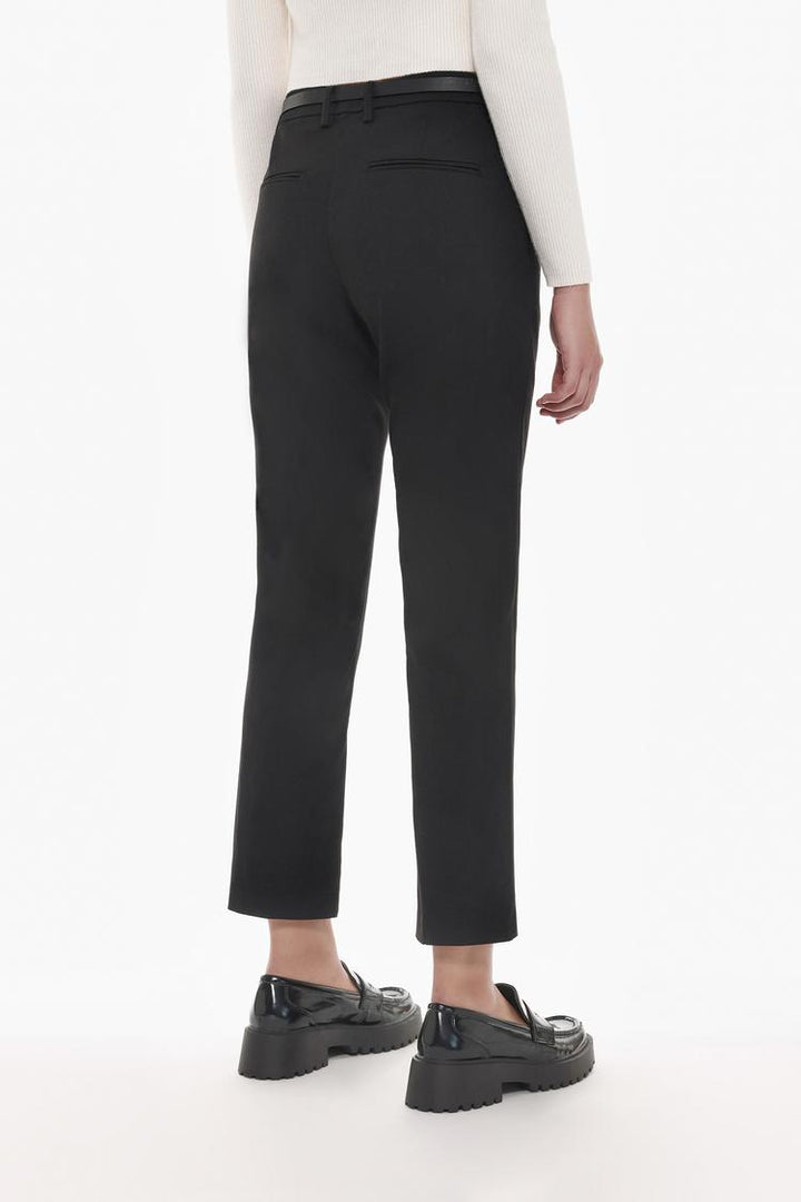 Full-body display of black slim fit trousers with a belt, styled for timeless fashion