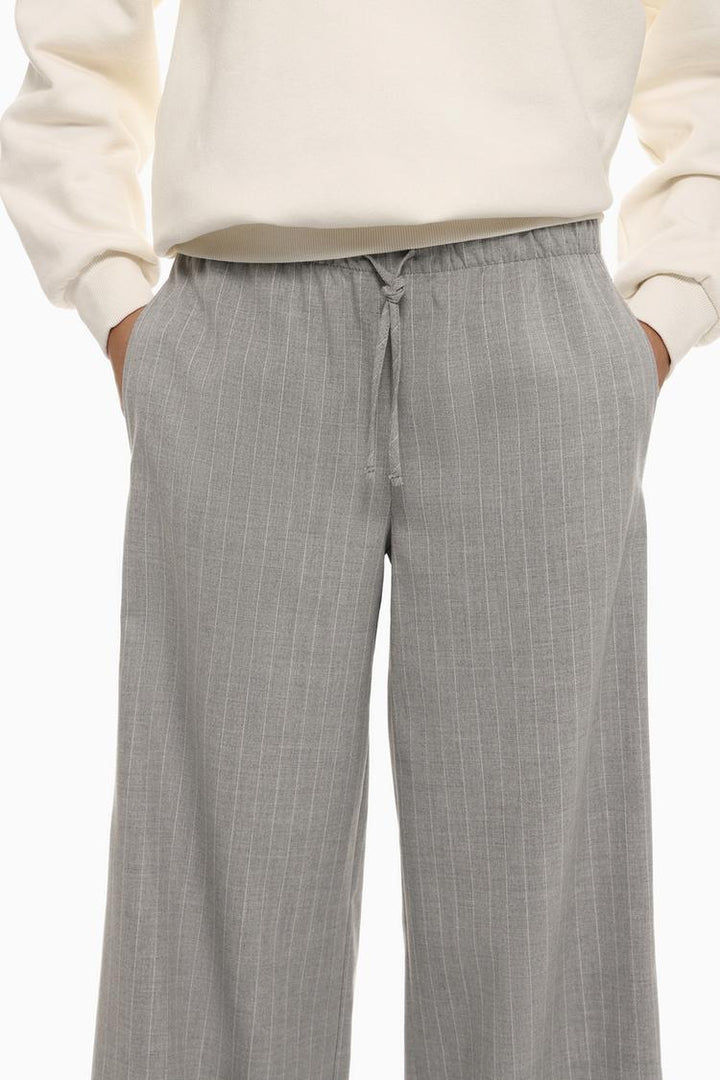 Full-body display of grey smart trousers with a waistband, styled for versatile elegance