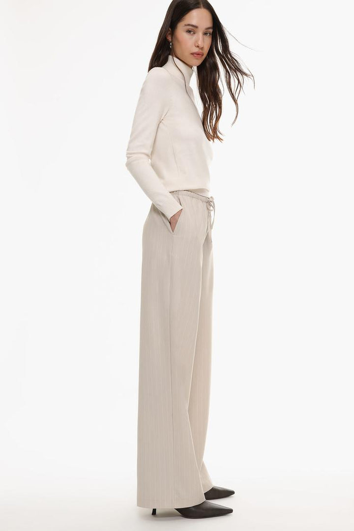 Side view of beige straight-fit trousers, showcasing detailed design and contemporary fit