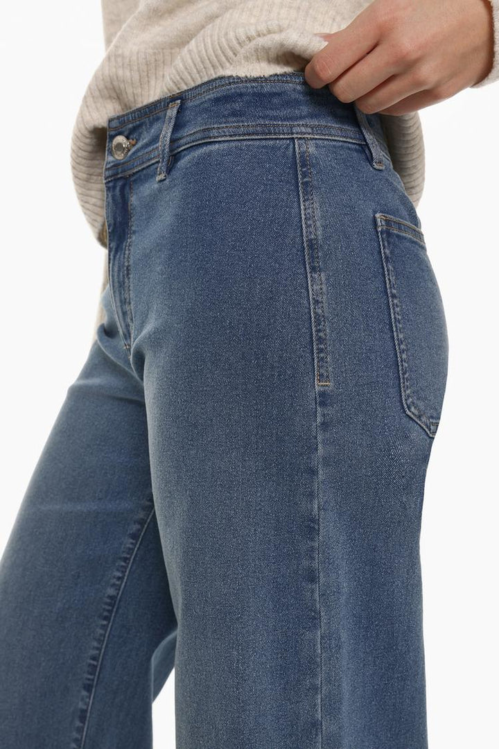 Side profile emphasizing the flow and movement of the denim fabric.