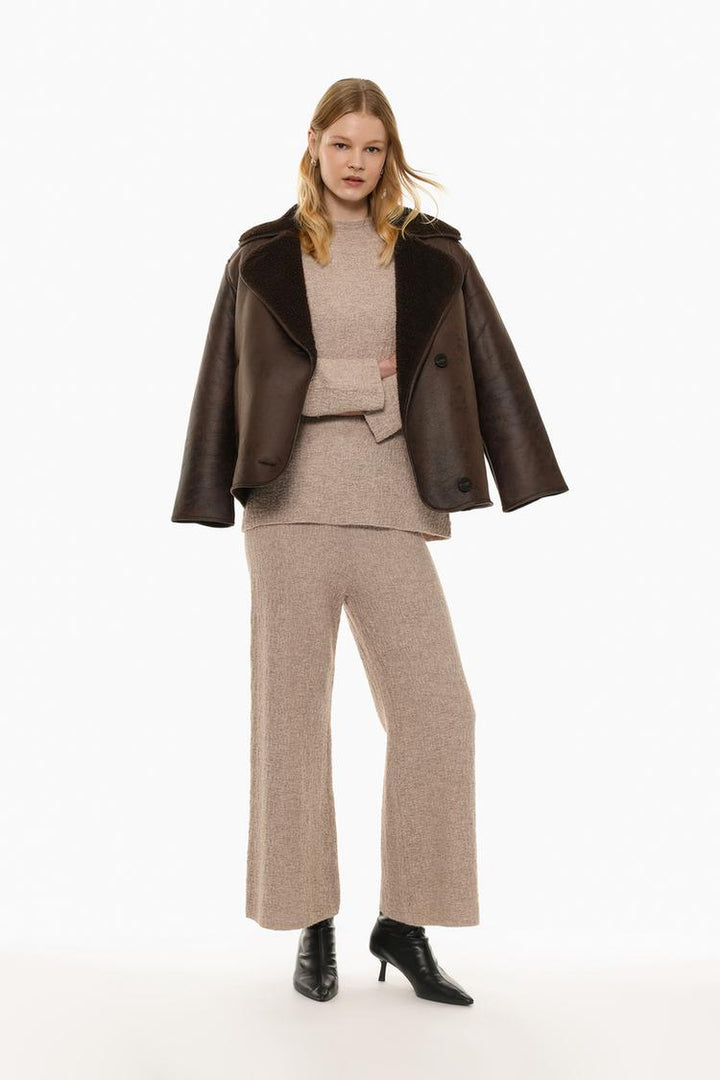 Highlighting textured knit trousers in beige, with a neutral and elegant aesthetic.