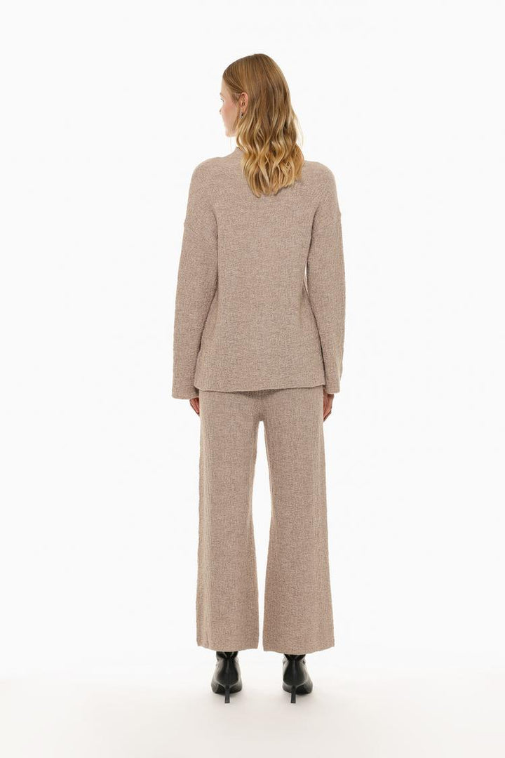 Back view of the beige textured knit trousers, emphasizing the rear knit design.