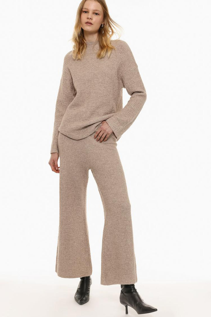 Full-body image of the beige textured knit trousers, showcasing their fit and flow.