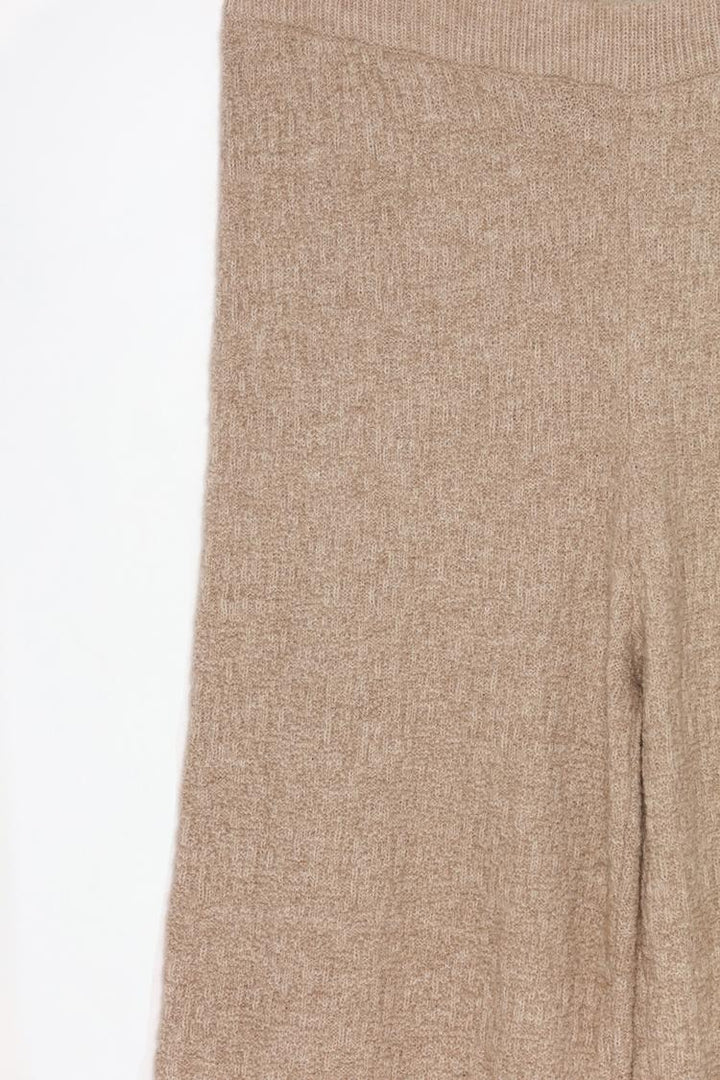 Close-up image of the beige textured knit trousers, emphasizing texture and detailing.