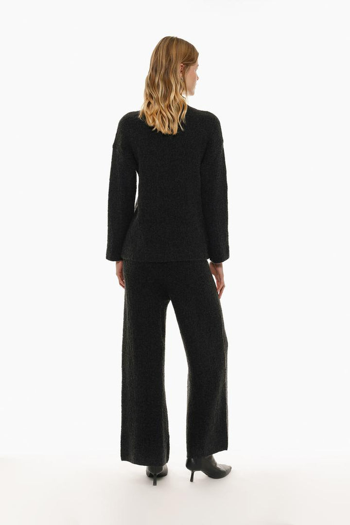 Rear view of the black textured knit trousers, showcasing their stylish fit and knit pattern.