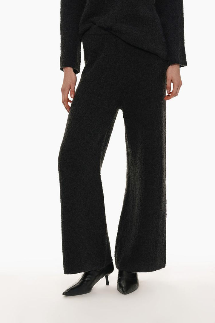 Front view of the black textured knit trousers, focusing on the waistband and textured design.