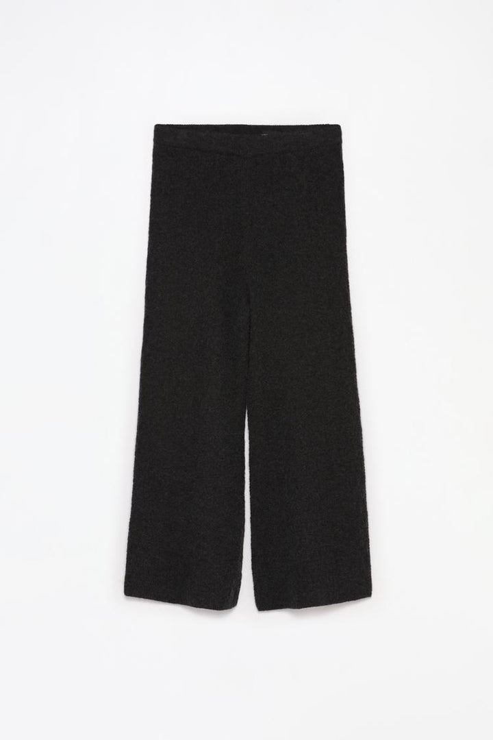 Detailed full product image of the black textured knit trousers, highlighting their overall appeal.