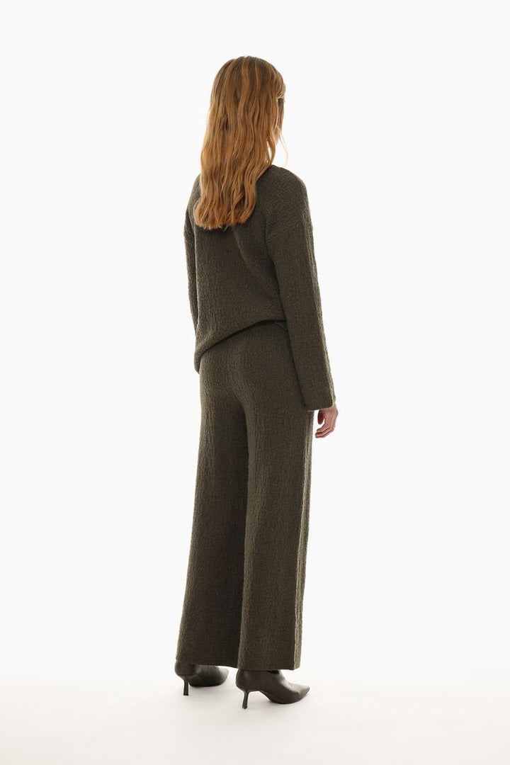 Back view of the textured knit trousers in green, highlighting the rear fit and details.