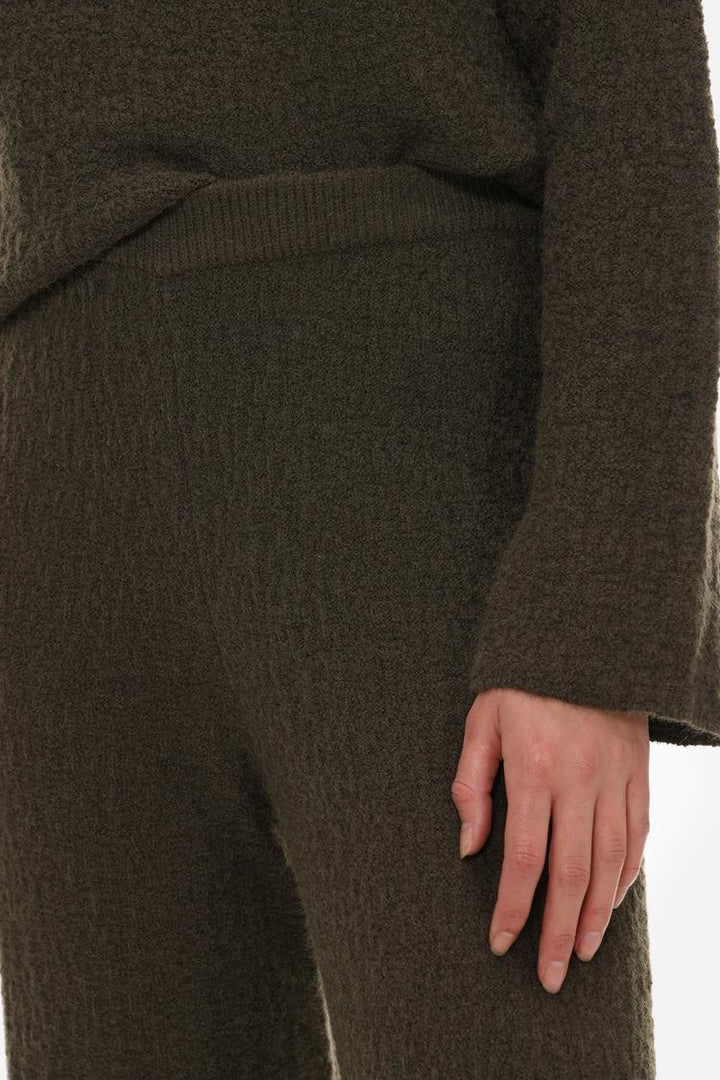 Styled look featuring the textured knit trousers in green, showing how they can be paired with other outfits.