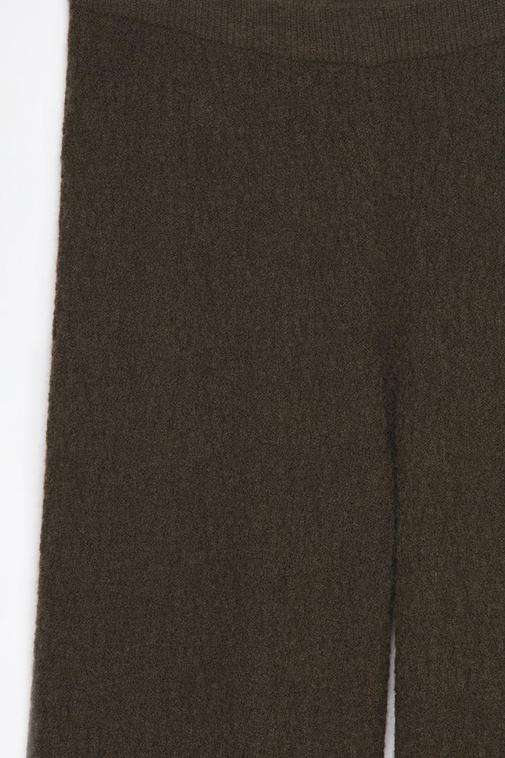 Close-up product image of the green textured knit trousers, focusing on fabric details and craftsmanship.