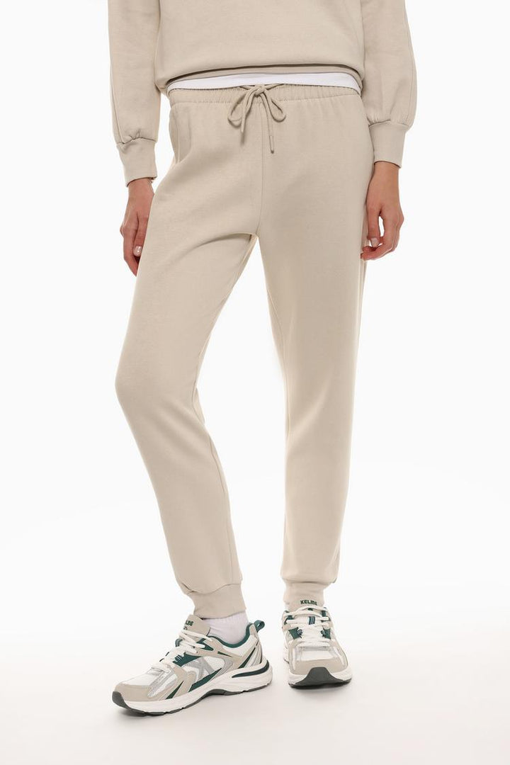 Front view of beige tracksuit bottoms, emphasizing the waist and leg fit.