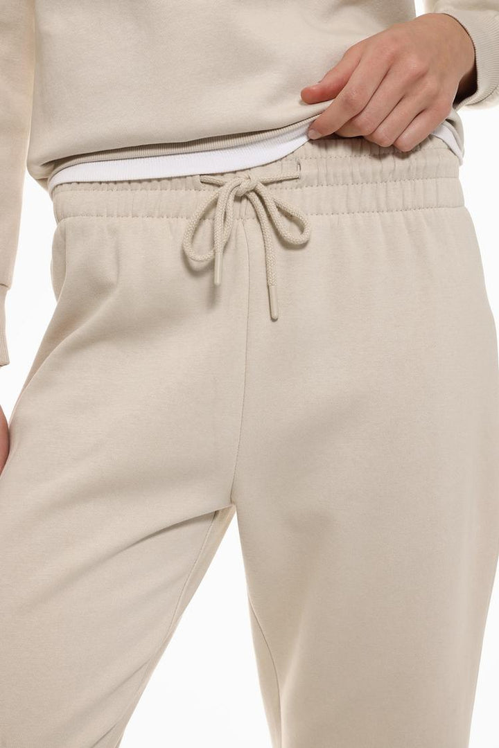 Close-up view of beige tracksuit bottoms to show fabric and details.