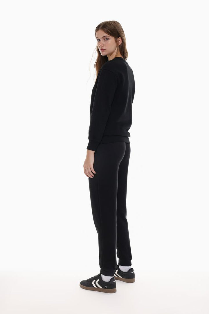 Side view of black tracksuit bottoms emphasizing the overall cut.