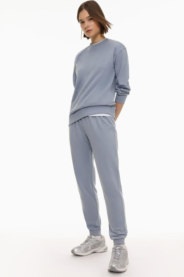 Full body view of blue tracksuit bottoms worn by a model to show fit.