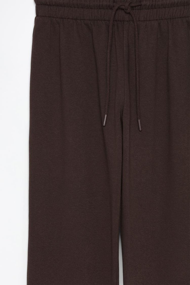 Tracksuit bottoms brown product image showcasing the relaxed fit, elastic waistband, and versatile design perfect for lounging or casual outings.