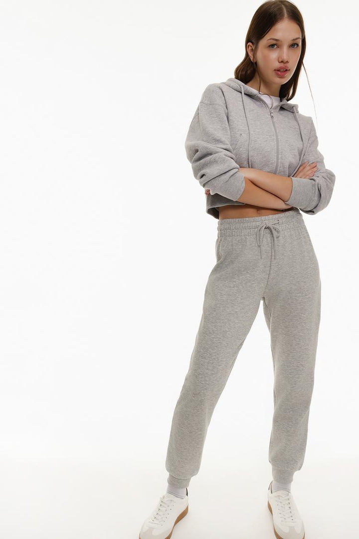 Body side view of grey tracksuit bottoms highlighting the waist and leg fit.