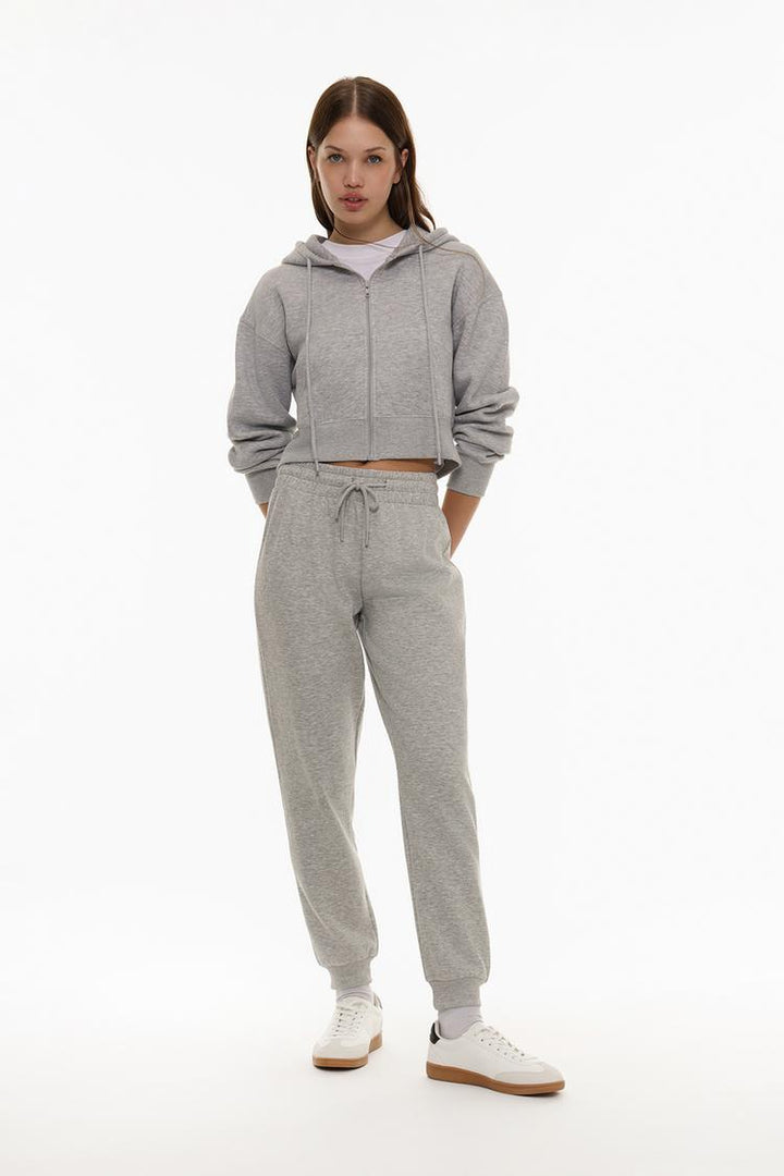 Full body view of grey tracksuit bottoms worn by a model, showcasing fit and style.