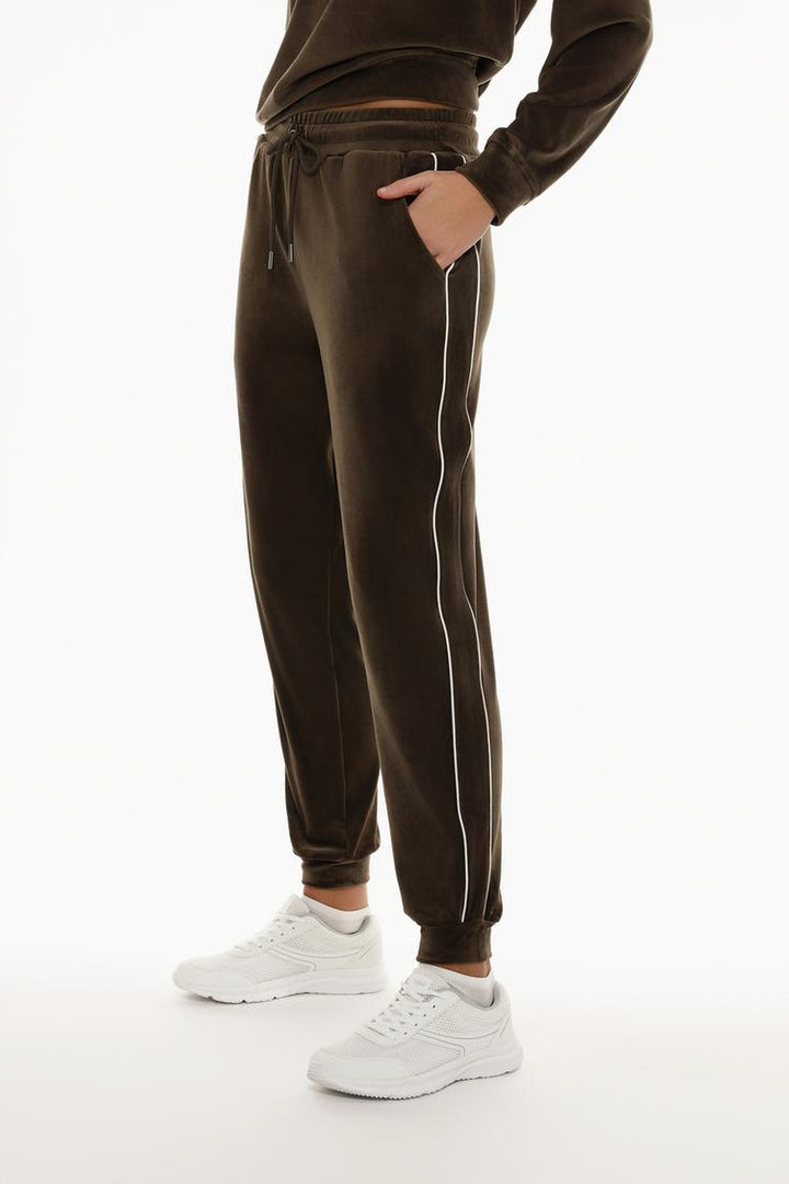 Body shot of brown velvet joggers emphasizing the fit and style.