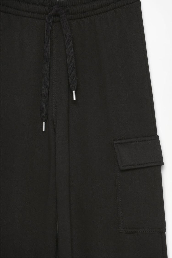 Close-up image of the black wide-leg cargo trousers, focusing on details such as the fabric texture, stitching, and pocket design.