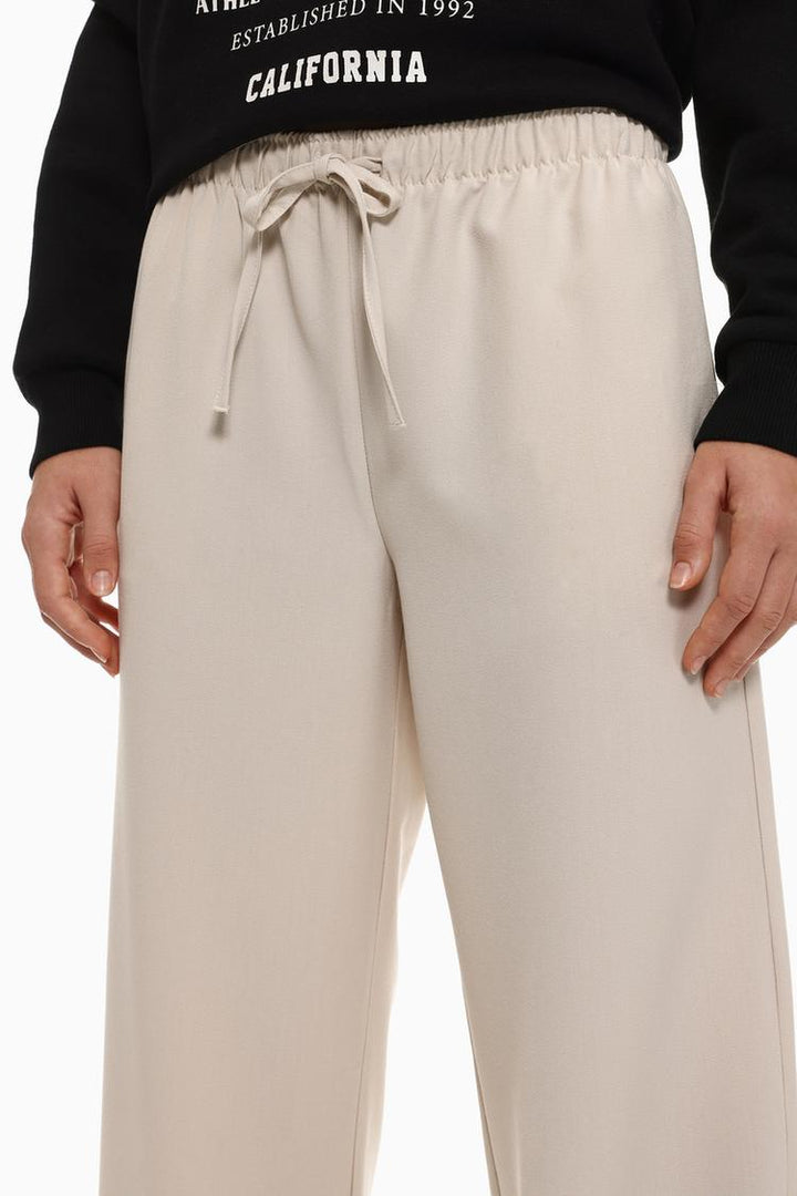 Full-body view of beige wide-leg smart trousers, providing a chic and elegant fit