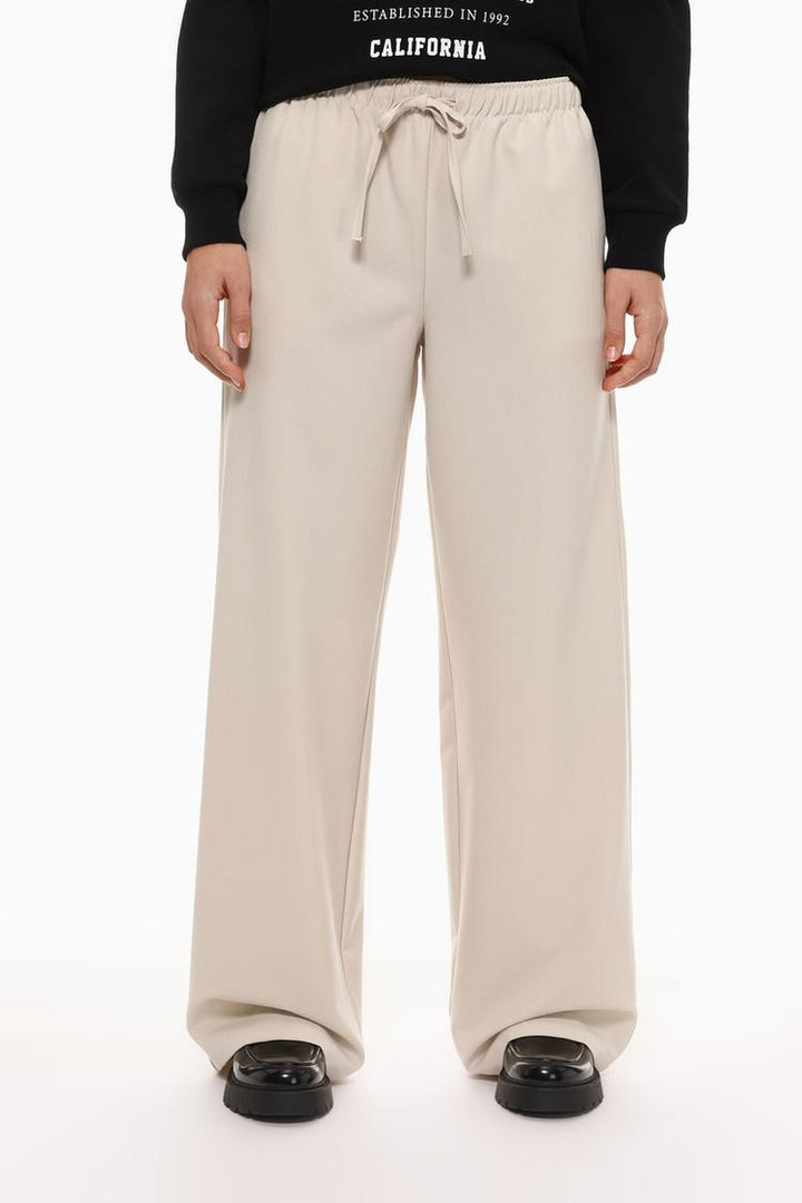 Front view of beige wide-leg smart trousers, showcasing their sleek design and refined look