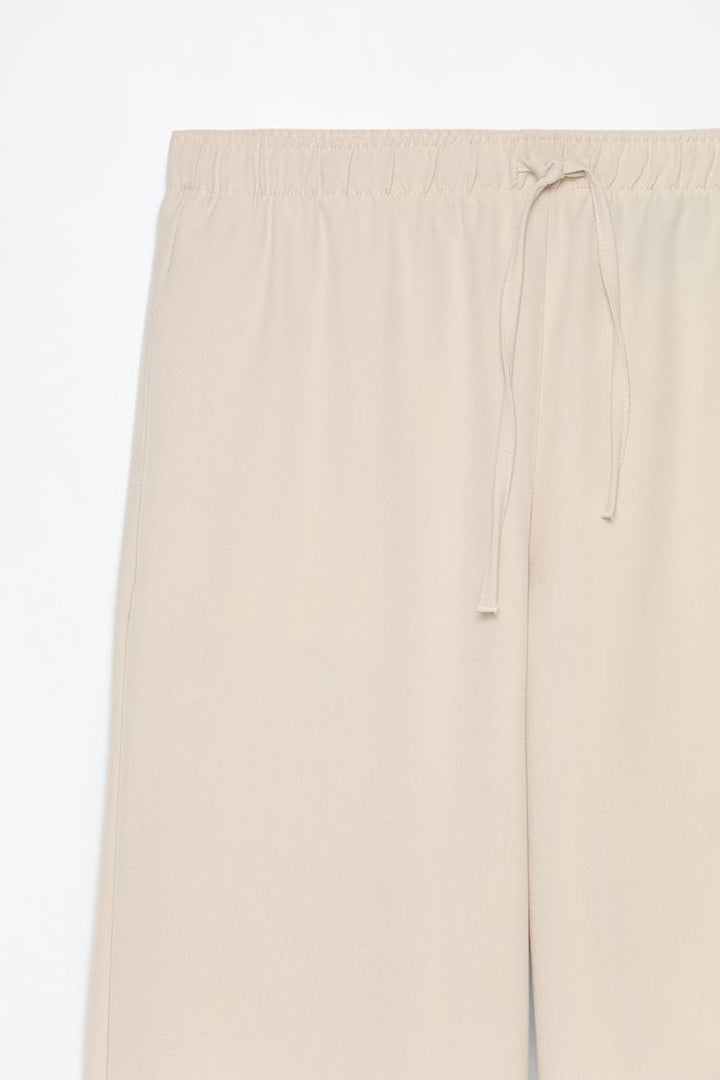 Product shot of beige wide-leg smart trousers, designed for a contemporary and polished appearance