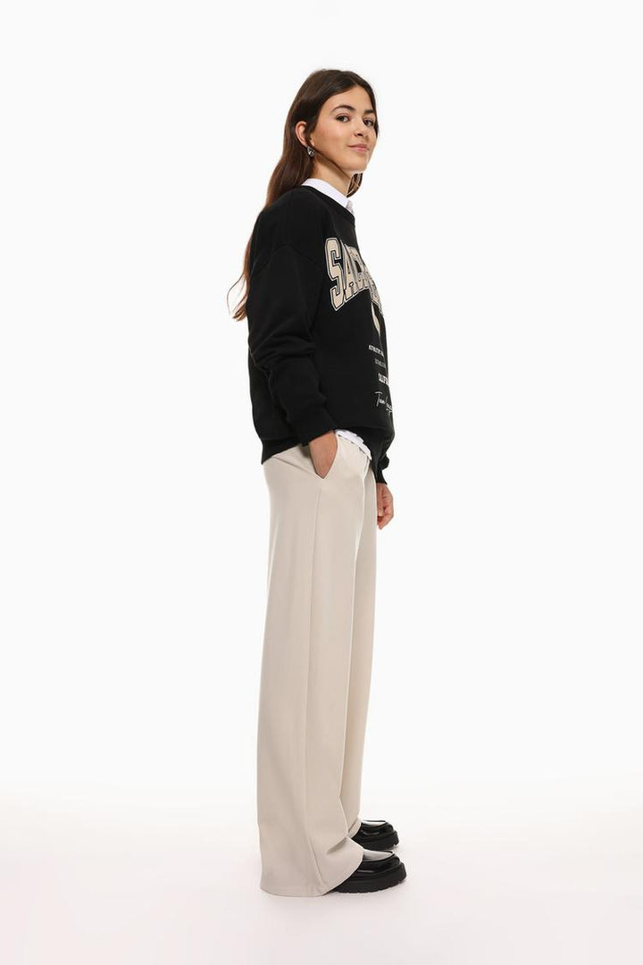 Side view of beige wide-leg smart trousers, emphasizing the relaxed and tailored silhouette