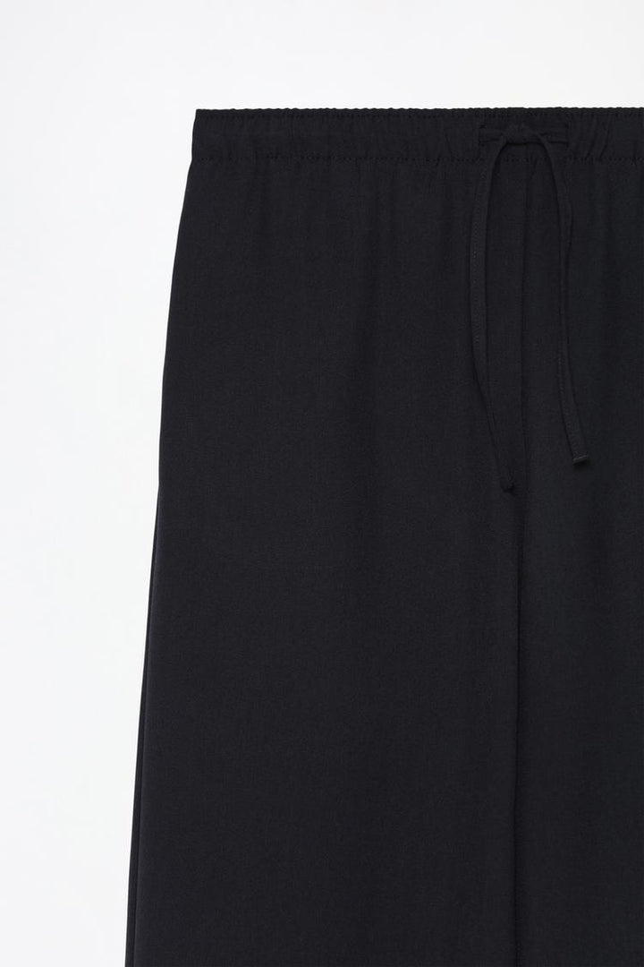 Product shot of black wide-leg smart trousers, perfect for a polished and sophisticated look